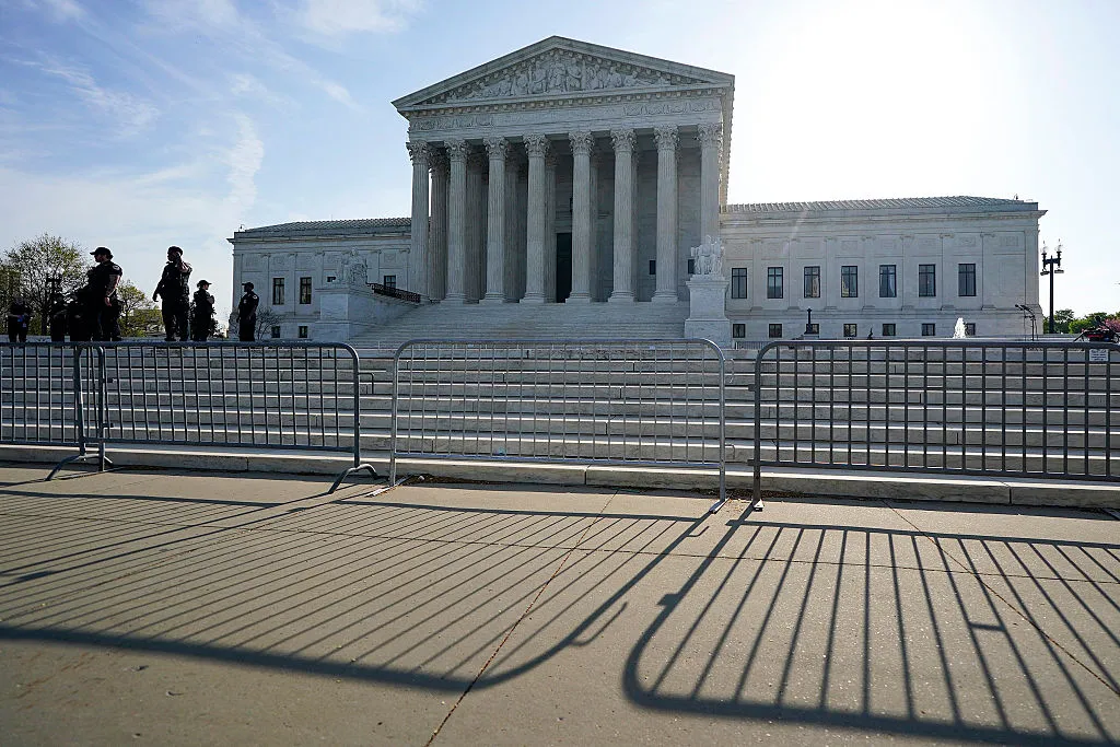 The United States Supreme Court building on a clear morning with people gathered on the front plaza, news photography style