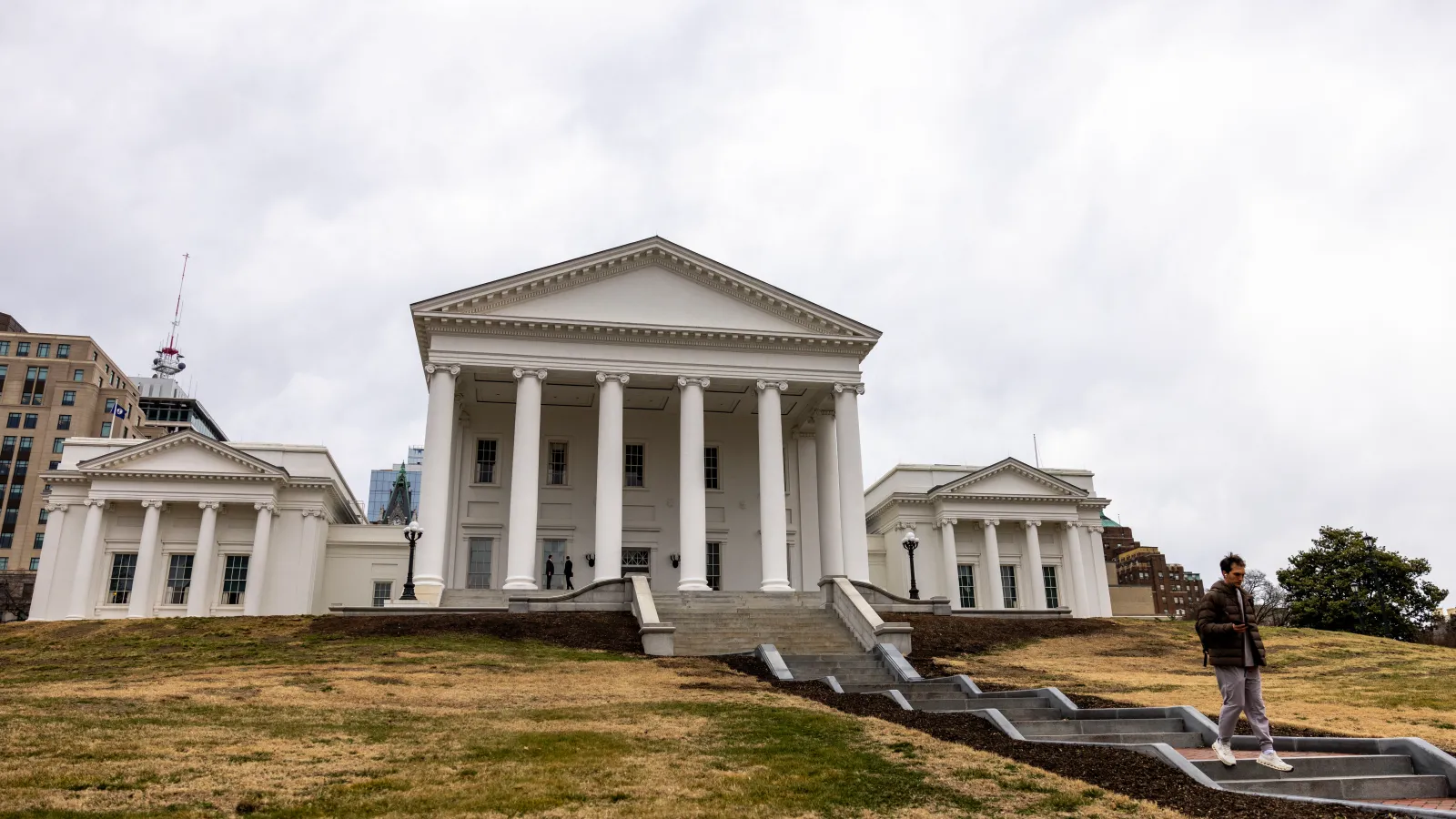 The Virginia State Capitol building in Richmond on a clear spring day with pedestrians on the grounds, news photography style