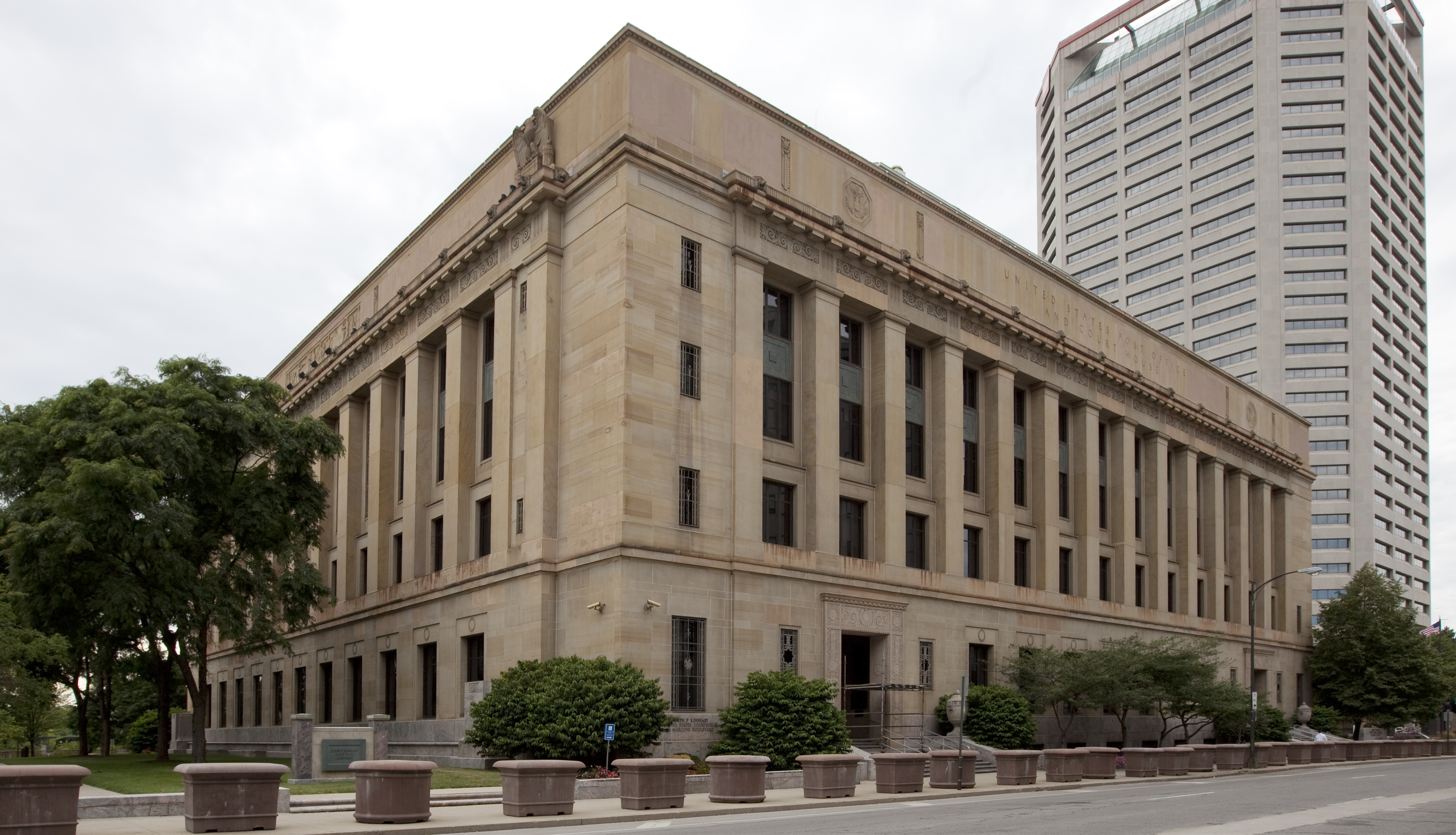 The exterior of a United States District Court building on a clear day, with people walking near the entrance, news photography style