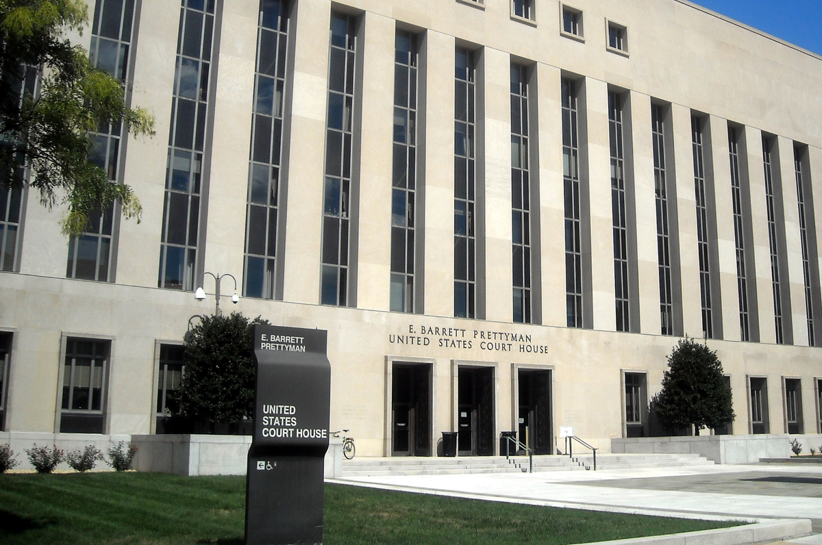 The exterior of a United States District Court building with a formal stone facade and entrance steps in daylight, documentary photography style