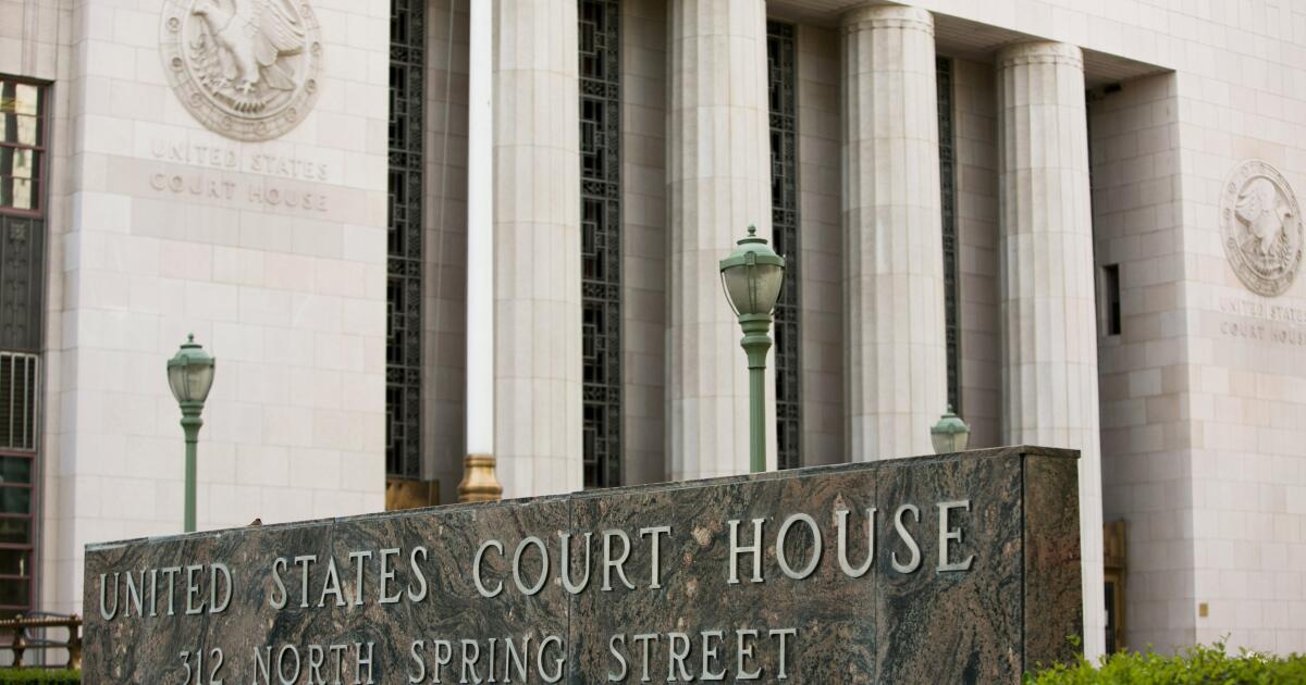 The exterior of a United States District Court building, with courthouse signage visible and people walking nearby