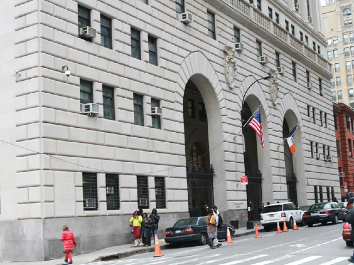 The exterior of a busy county criminal courthouse in New York County during daytime with pedestrians and security barriers, news photography style