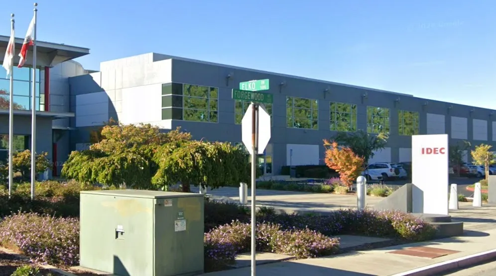 The exterior of a modern technology company office building with people walking nearby on a clear day, realistic news photography style