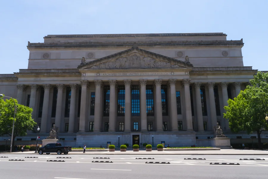 The exterior of the National Archives building in Washington, D.C., photographed in daylight with visitors nearby, news photography style