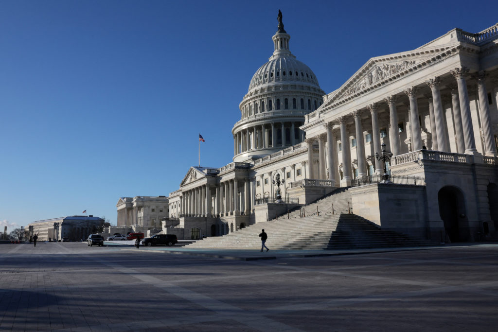 The exterior of the United States Capitol building seen from ground level in daylight, with steps and columns visible, news photography style