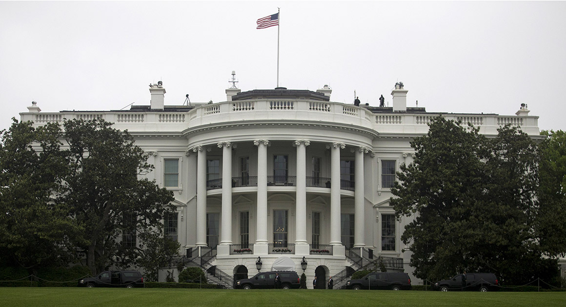 The exterior of the White House seen from the North Lawn with the press area and security perimeter visible in the foreground