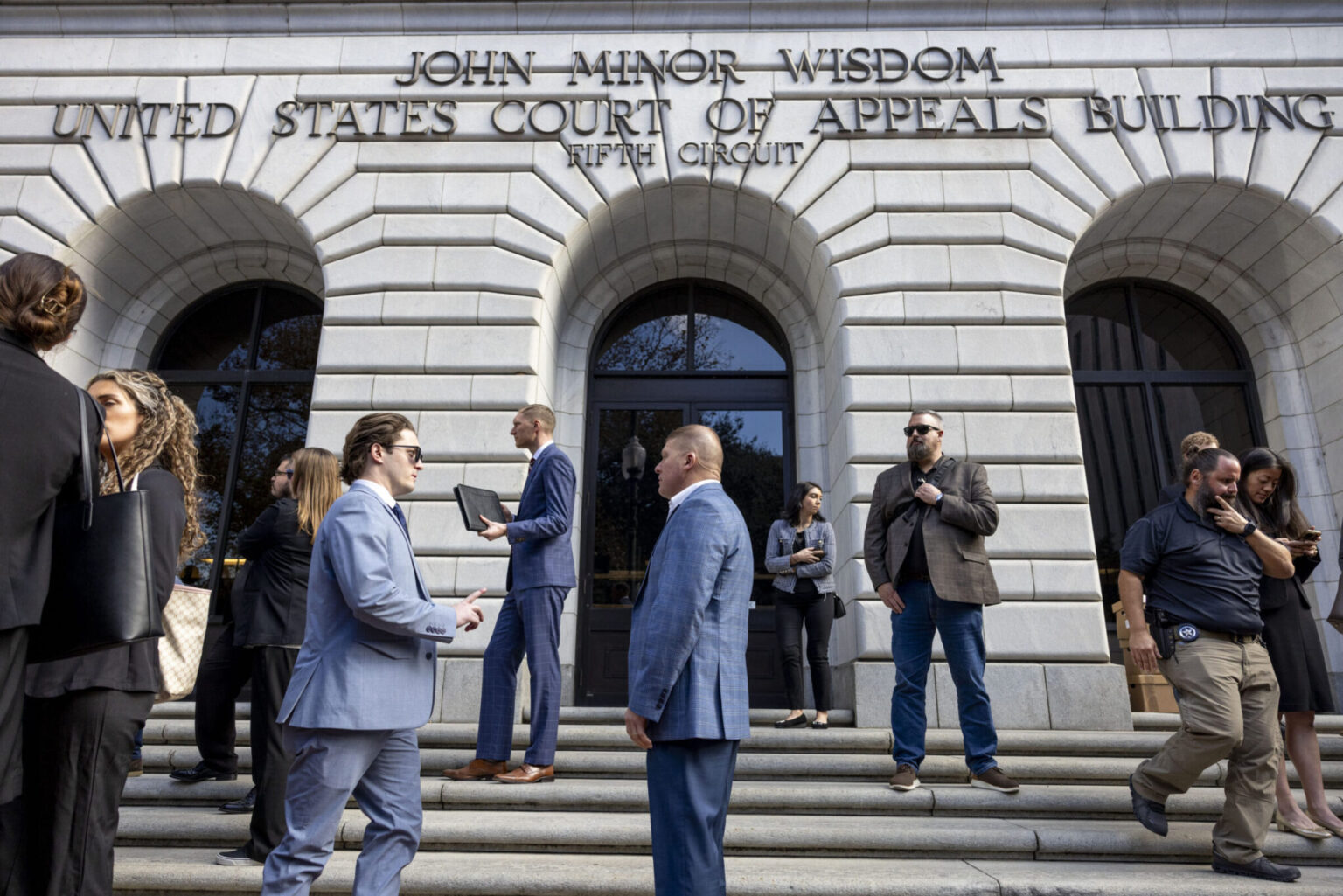 The exterior of the federal appeals courthouse in New Orleans on a clear day, with pedestrians nearby, news photography style