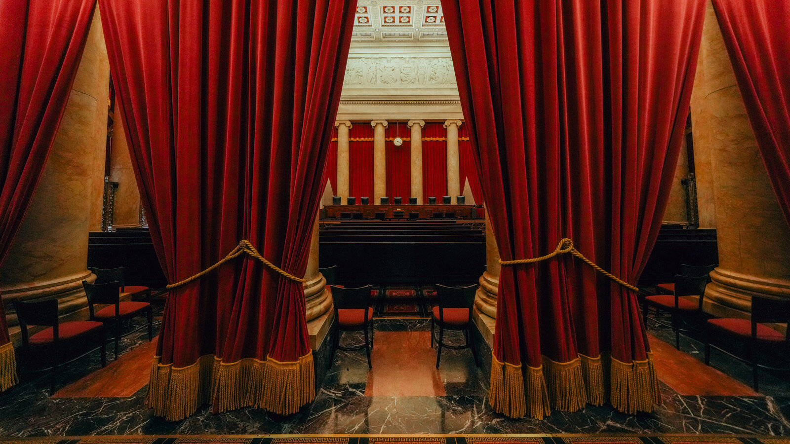 The interior of the United States Supreme Court courtroom with empty benches and the elevated bench in view, photographed in soft indoor lighting, news photography style