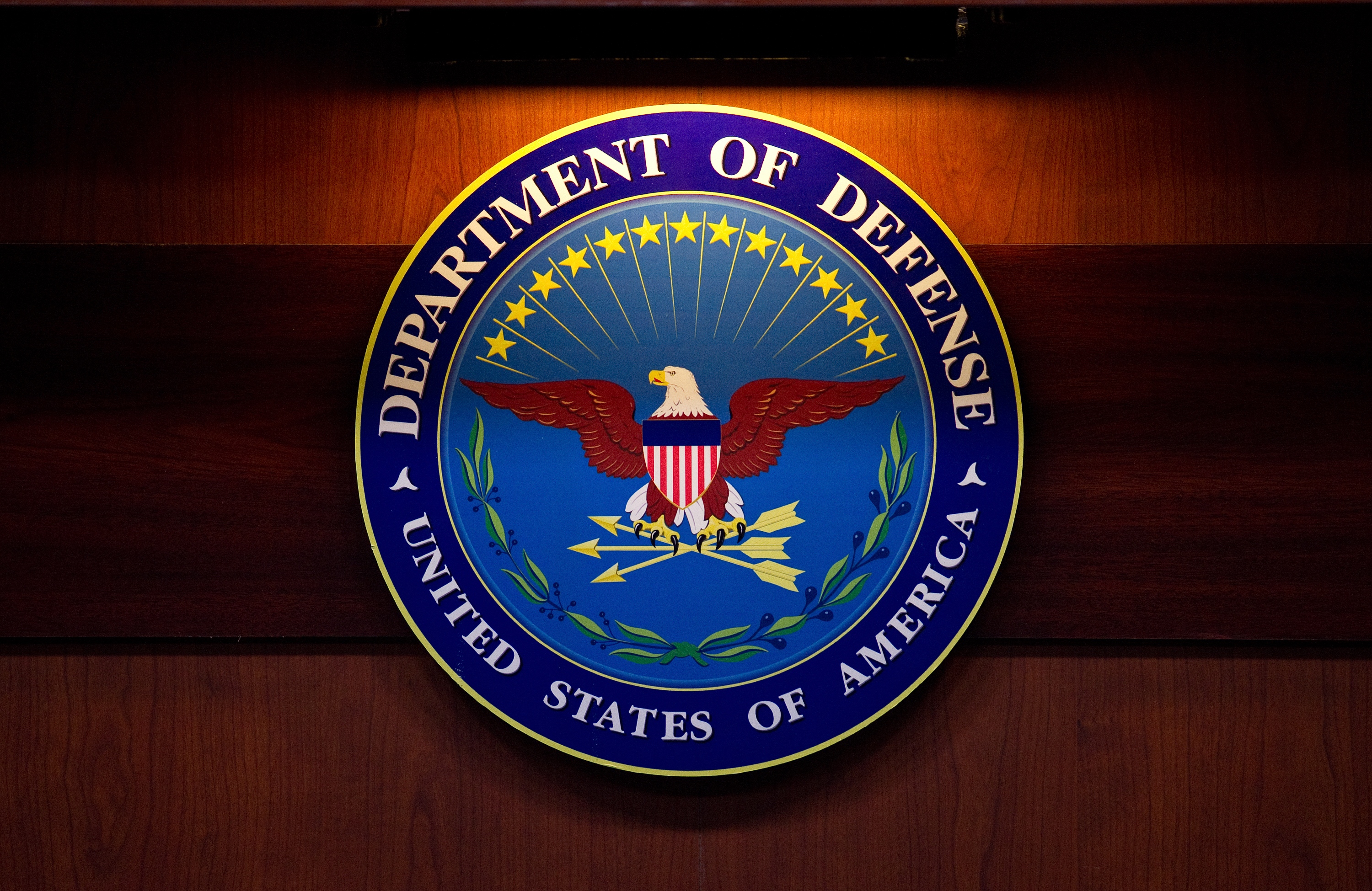 The seal of the U.S. Department of Defense displayed on an official backdrop