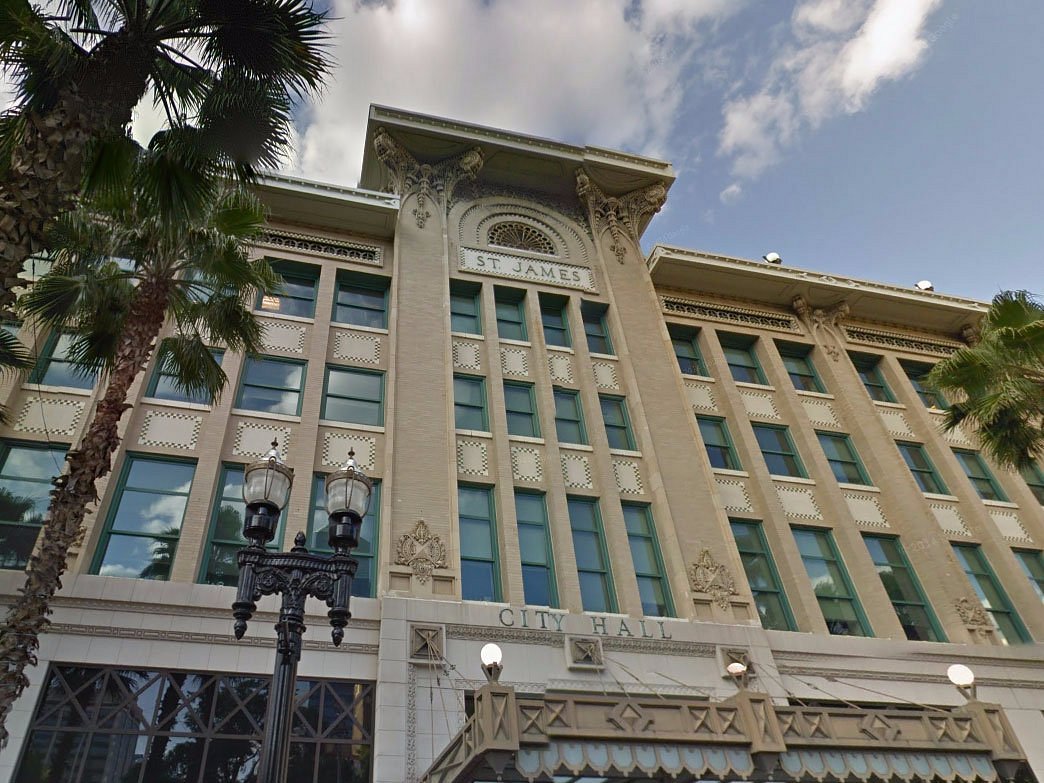 The security screening entrance of a Jacksonville city government building, with a metal detector and uniformed security staff near the doorway, news photography style