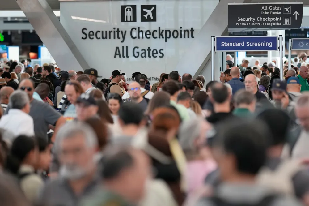 Travelers waiting in line at a TSA airport security checkpoint during a federal funding lapse, candid news photography style