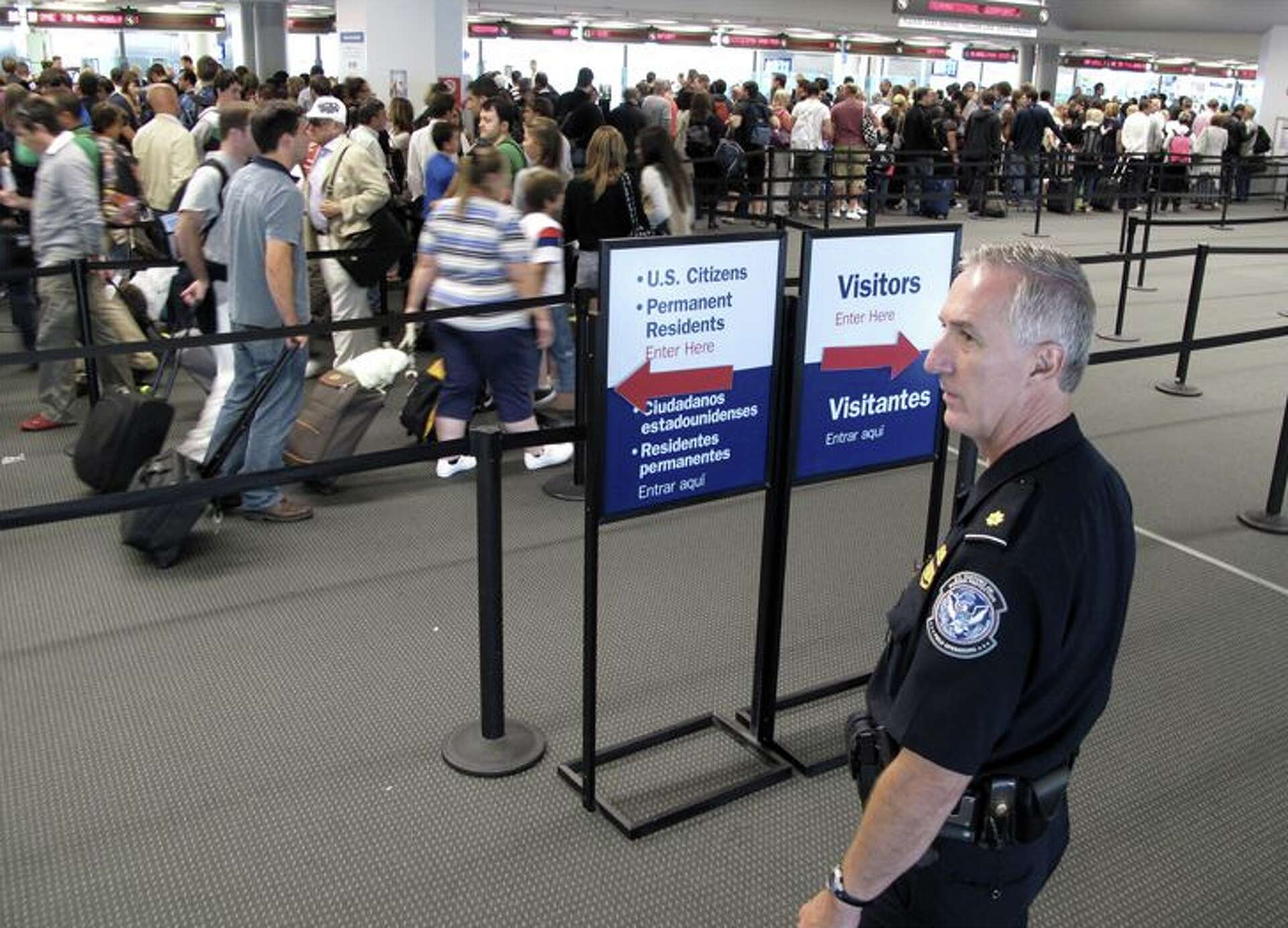 Travelers waiting near U.S. Customs and Border Protection passport control booths in an airport arrivals hall