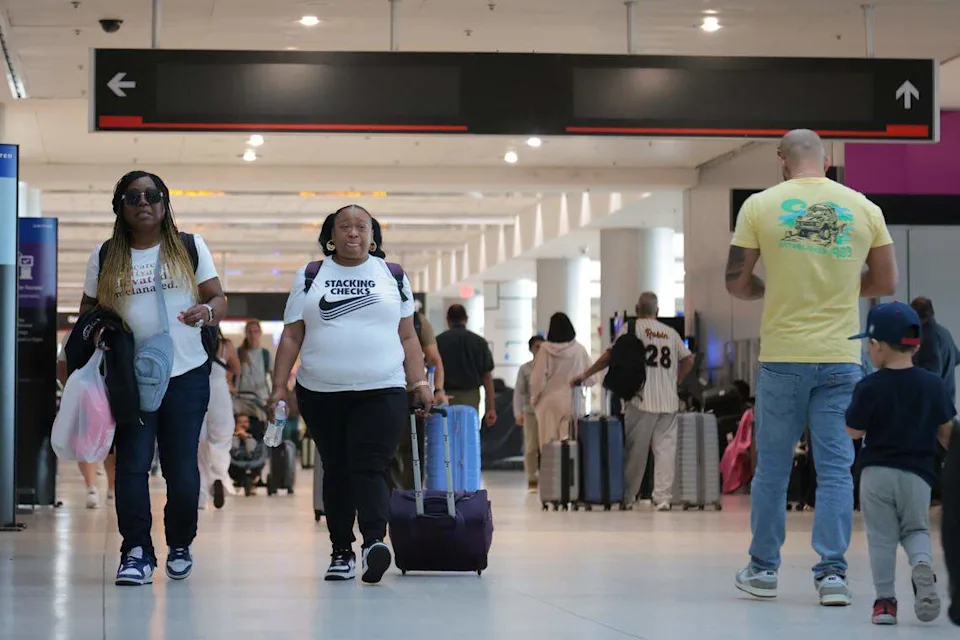 Travelers walking through a busy airport terminal concourse with rolling luggage, candid news photography style
