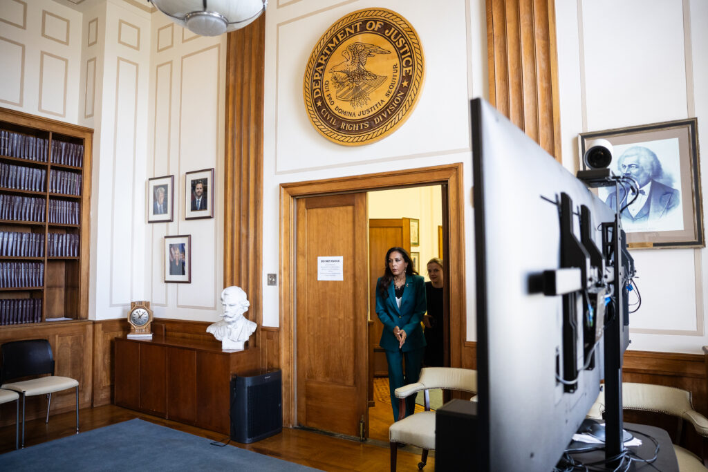 Two attorneys in a conference room reviewing printed documents spread on a table, with a laptop open beside them, candid photojournalism style