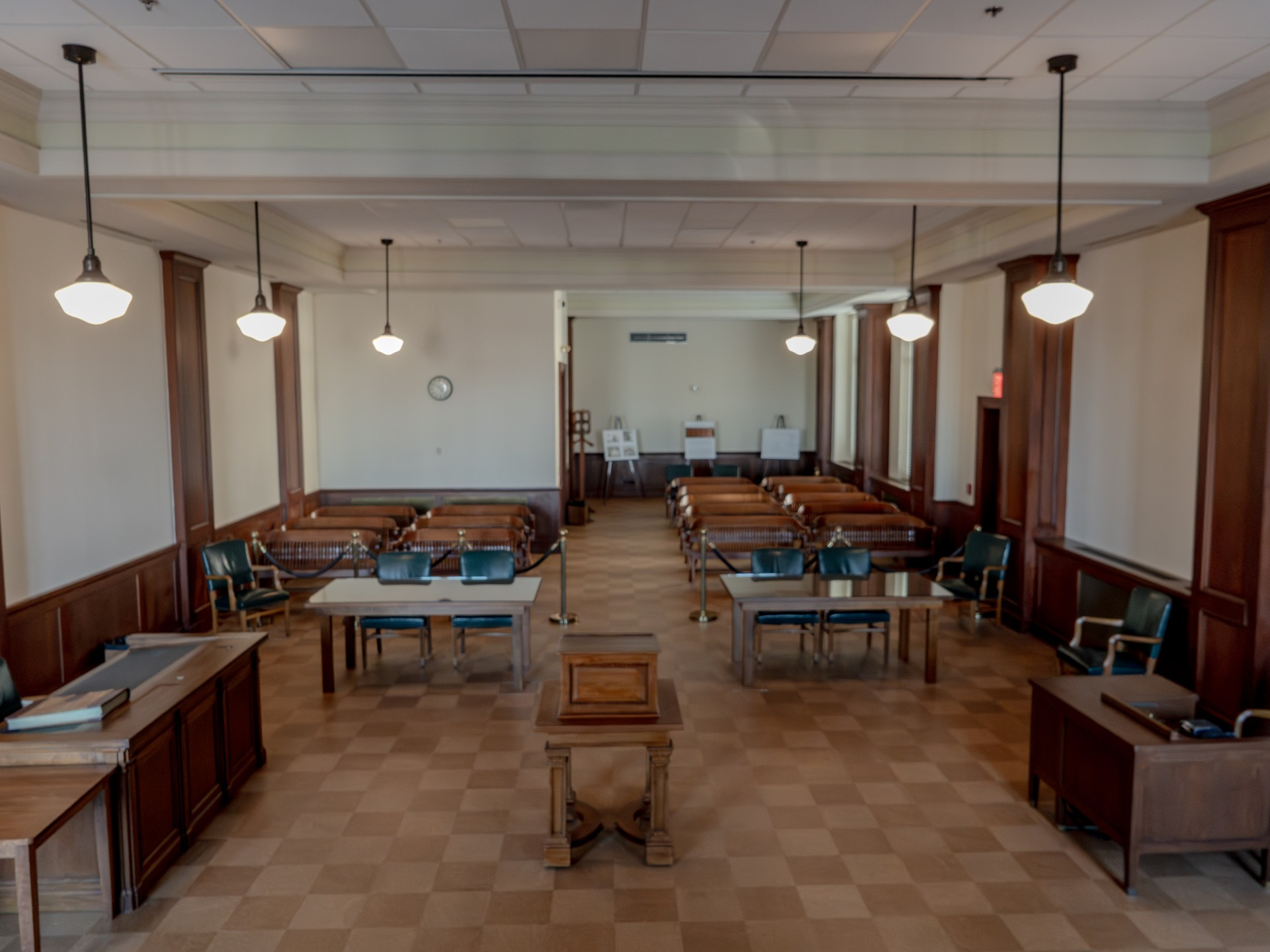 Two attorneys walking through a federal courthouse hallway carrying folders and a laptop after a civil hearing, candid news photo style