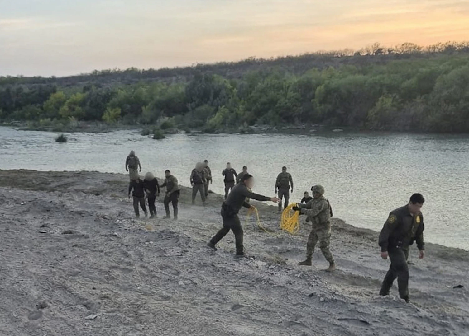 U.S. Border Patrol agents in uniform standing near patrol vehicles along a desert border area during an operation, news photography style
