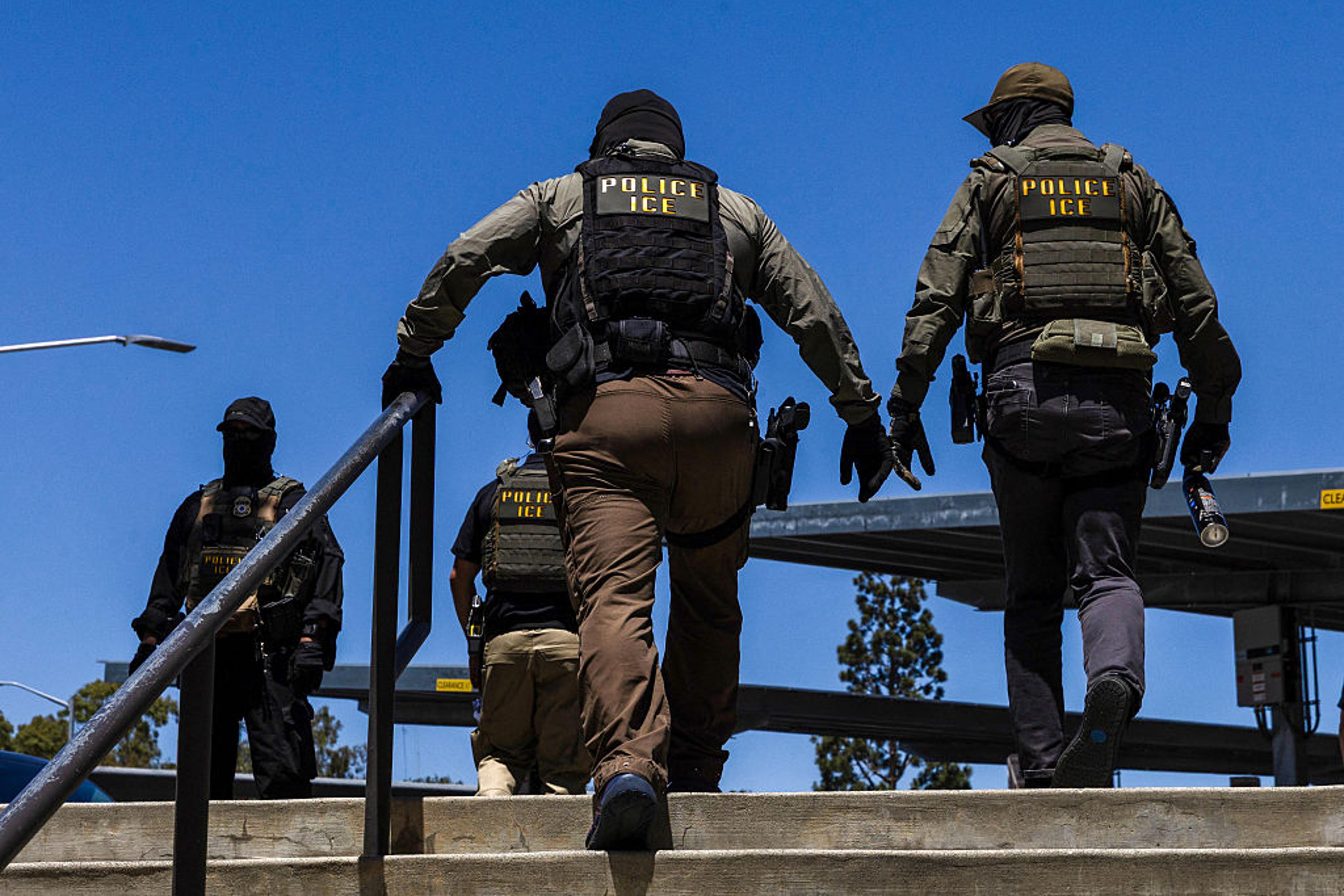 Uniformed ICE Enforcement and Removal Operations agents near marked federal vehicles during an immigration enforcement operation