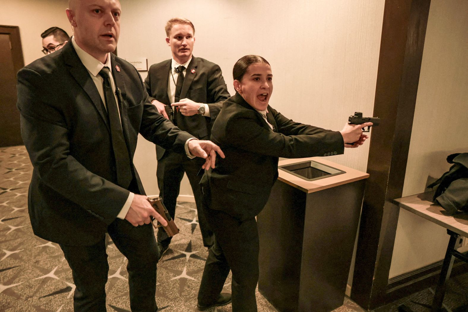 Uniformed security officers and police standing behind metal barricades outside a Washington, DC venue during the White House Correspondents’ Dinner weekend at night, news photography style