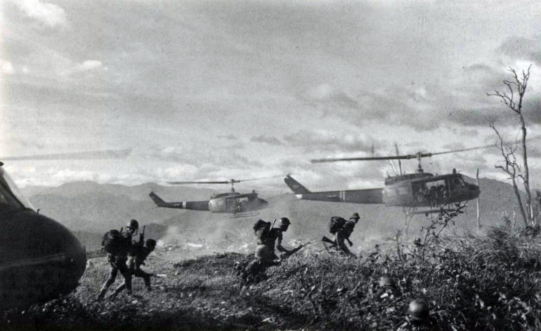 United States soldiers in combat uniforms loading equipment near a military helicopter on a dusty airfield, realistic historical photo style