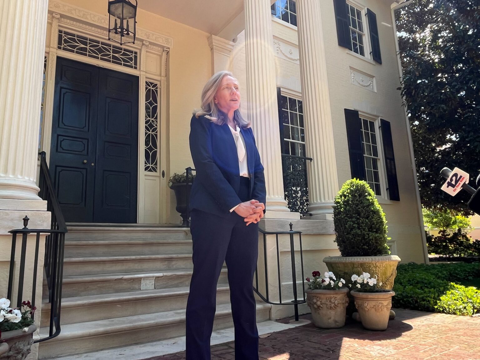 Virginia Governor Abigail Spanberger seated at a desk signing legislation with aides and lawmakers standing behind her in a Richmond office, news photography style