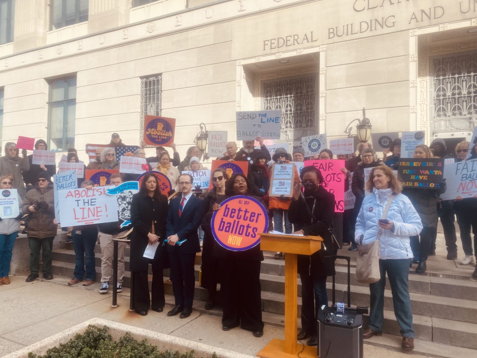 Voters and election observers gathered on the steps outside a federal courthouse on a clear morning, documentary news photograph style