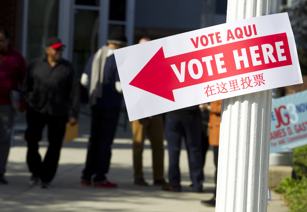 Voters standing in line outside a local polling place on Election Day, with poll workers near the entrance, news photography style