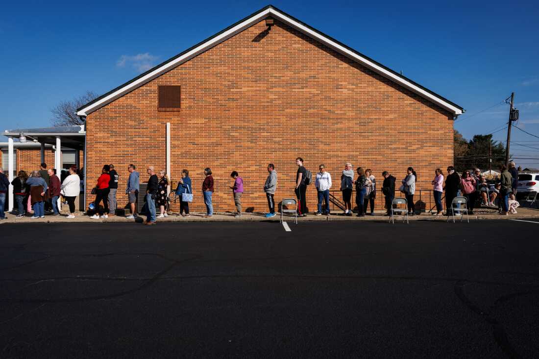 Voters standing in line outside a polling place in the United States during the November 2024 general election, news photography style