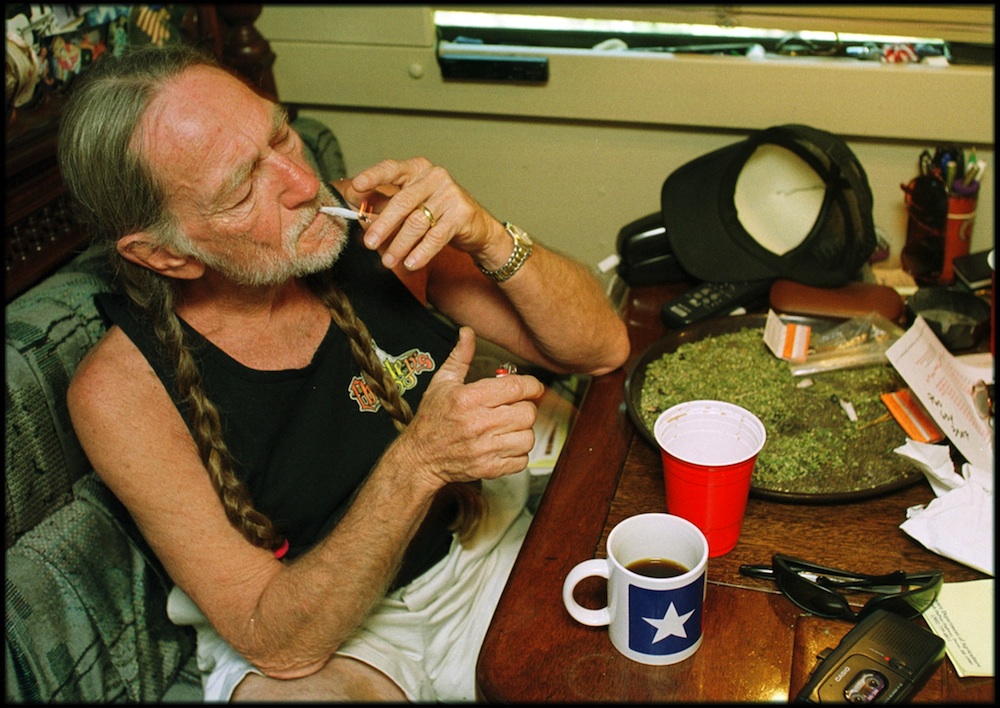 Willie Nelson seated in a kitchen wearing a red bandana, speaking directly to camera in a campaign-style endorsement video