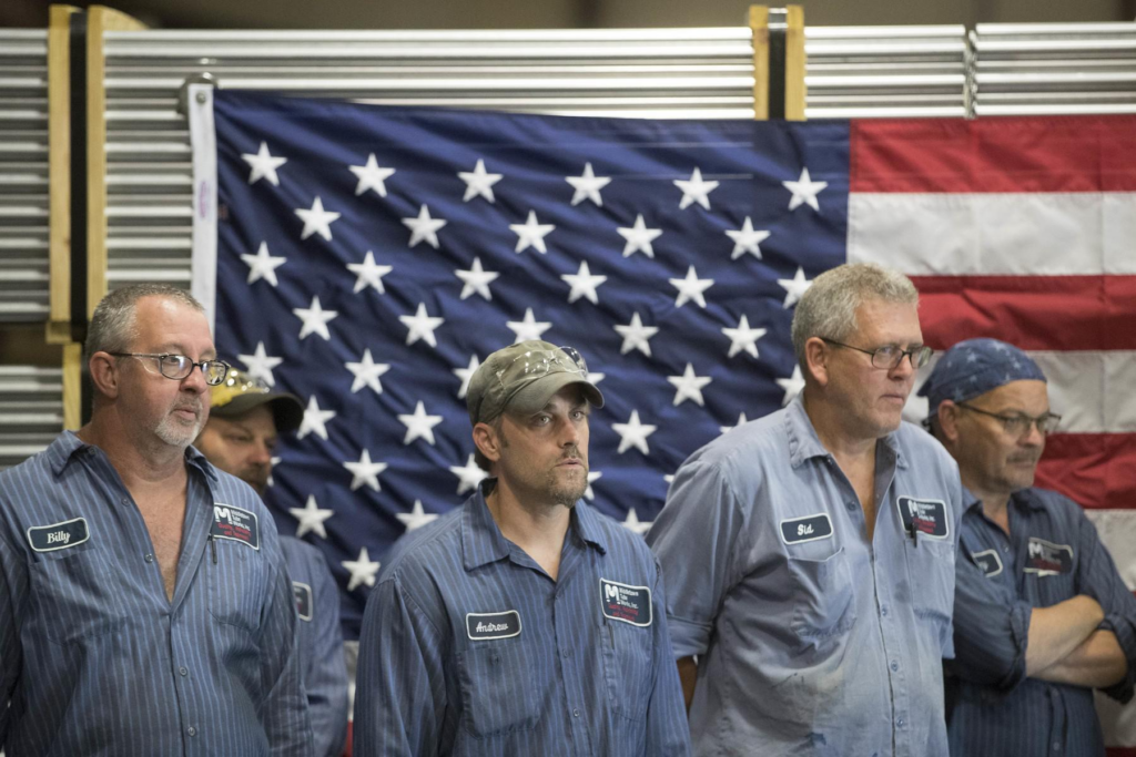 American steel workers in a bustling factory with American flags visible