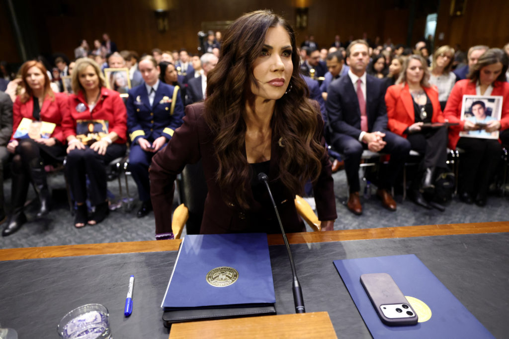 congressional hearing room with Noem testifying and representatives questioning