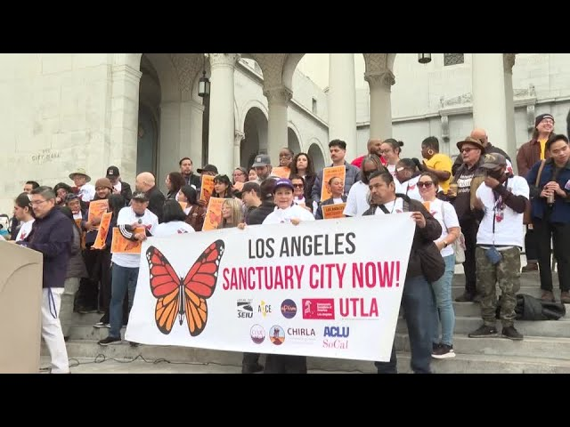 demonstraters holding up 'los angeles sanctuary city now' sign 