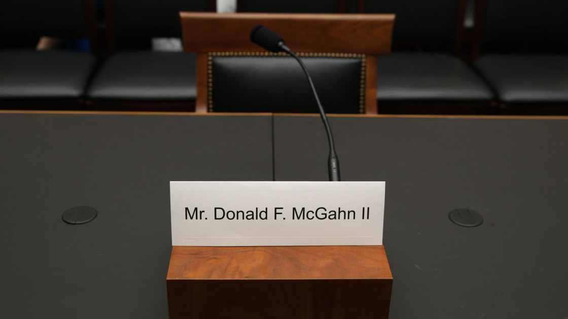 empty witness chair at congressional hearing table with nameplate and microphone