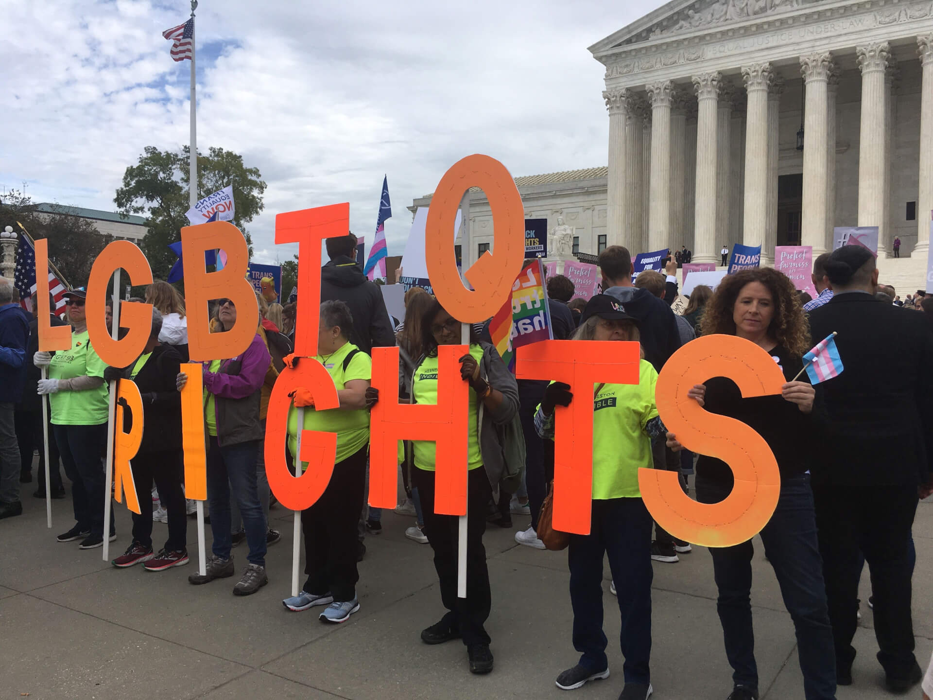 protestors outside Supreme Court with LGBTQ+ signs