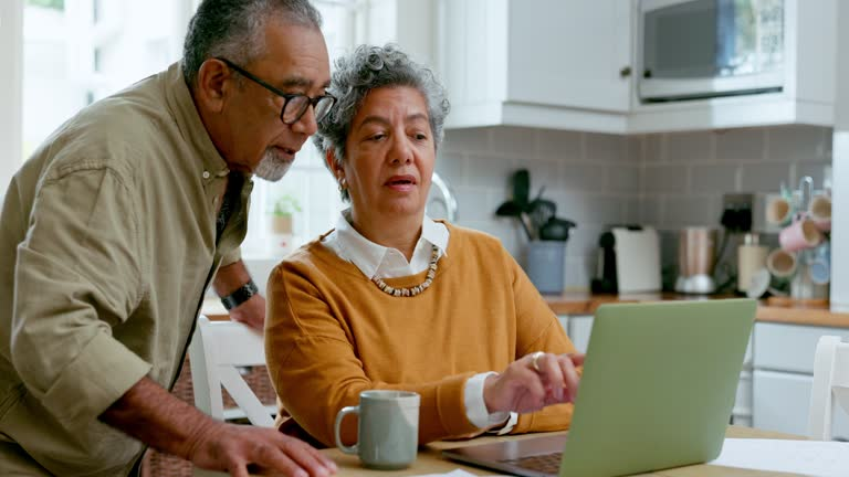 senior couple reading emails at kitchen table