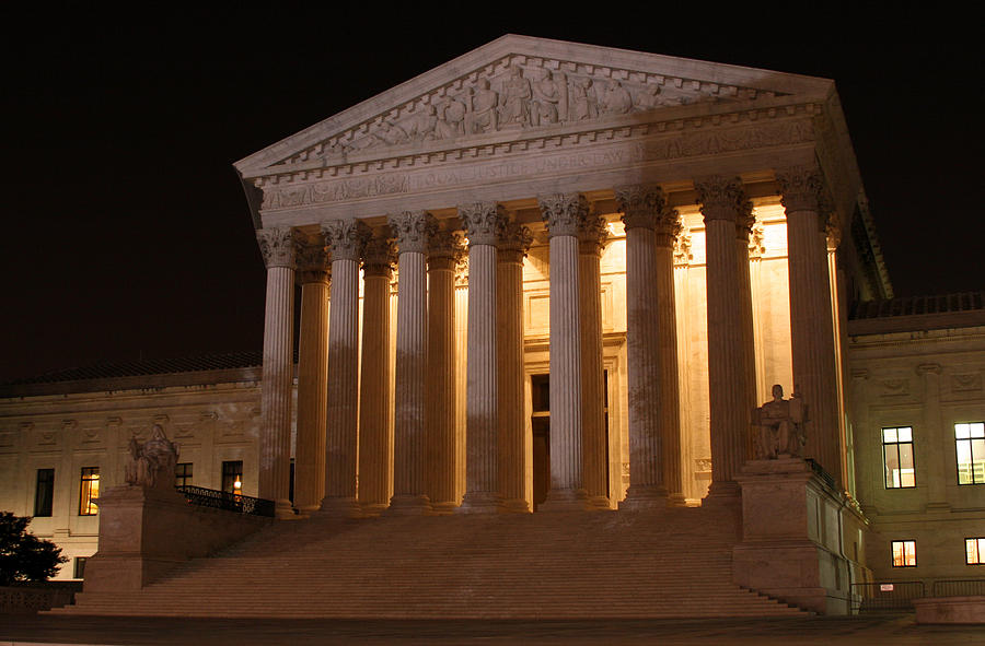 Supreme Court building at night with dramatic lighting and emergency vehicles