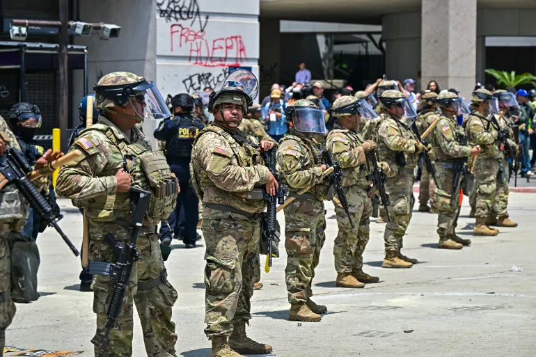 Police officers and members of the National Guard are deployed outside the Metropolitan Detention Center in downtown Los Angeles, US, June 8. [Frederic J Brown/AFP]