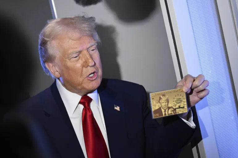 President Donald Trump holds up the $5m gold card as he speaks to reporters while on board Air Force One, en route to Miami, on April 3, 2025