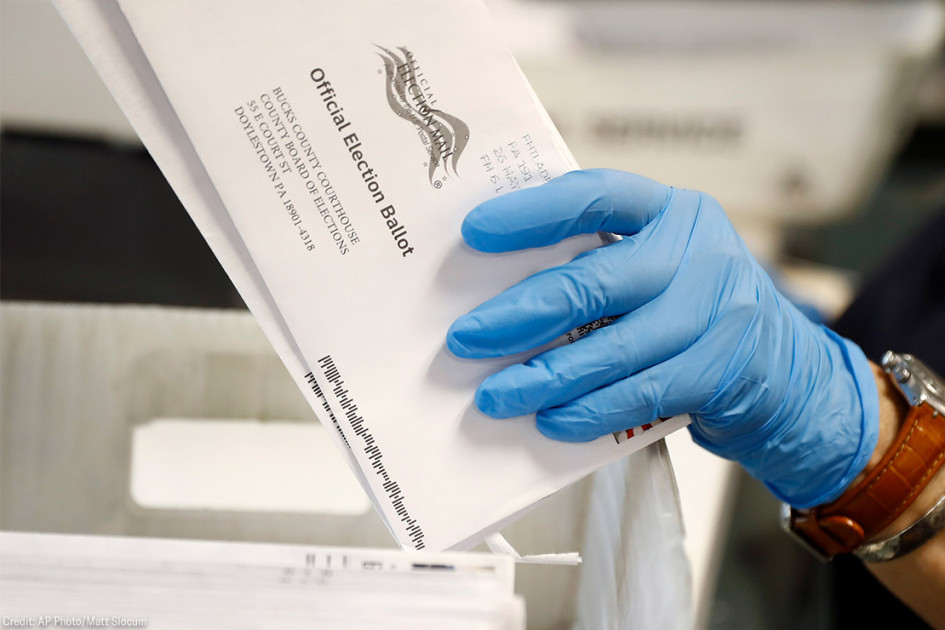 An election worker processes mail-in ballots