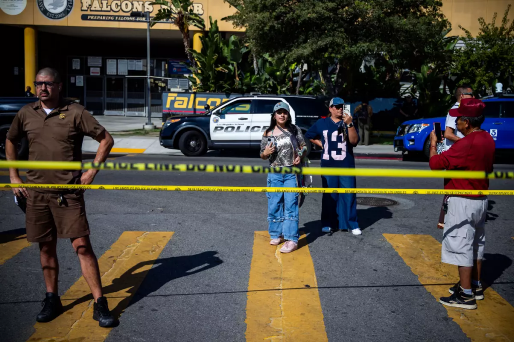 People watch at the scene of where a deputy U.S. marshal was wounded in South Los Angeles. (Ethan Swope/For The Times)
