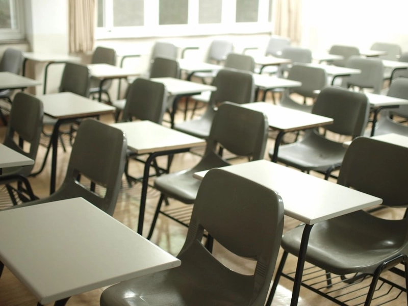 empty school classroom with desks and government funding termination letter on teacher's desk