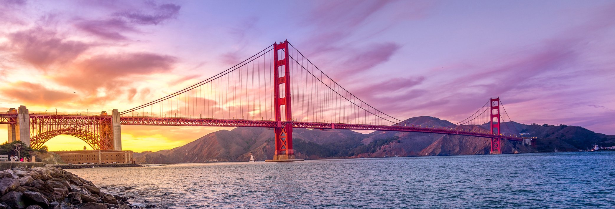 A sunset over the Pacific Ocean with the Golden Gate Bridge in the distance